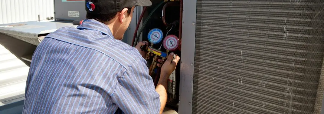 HVAC technician servicing a condenser unit in West Bradford
